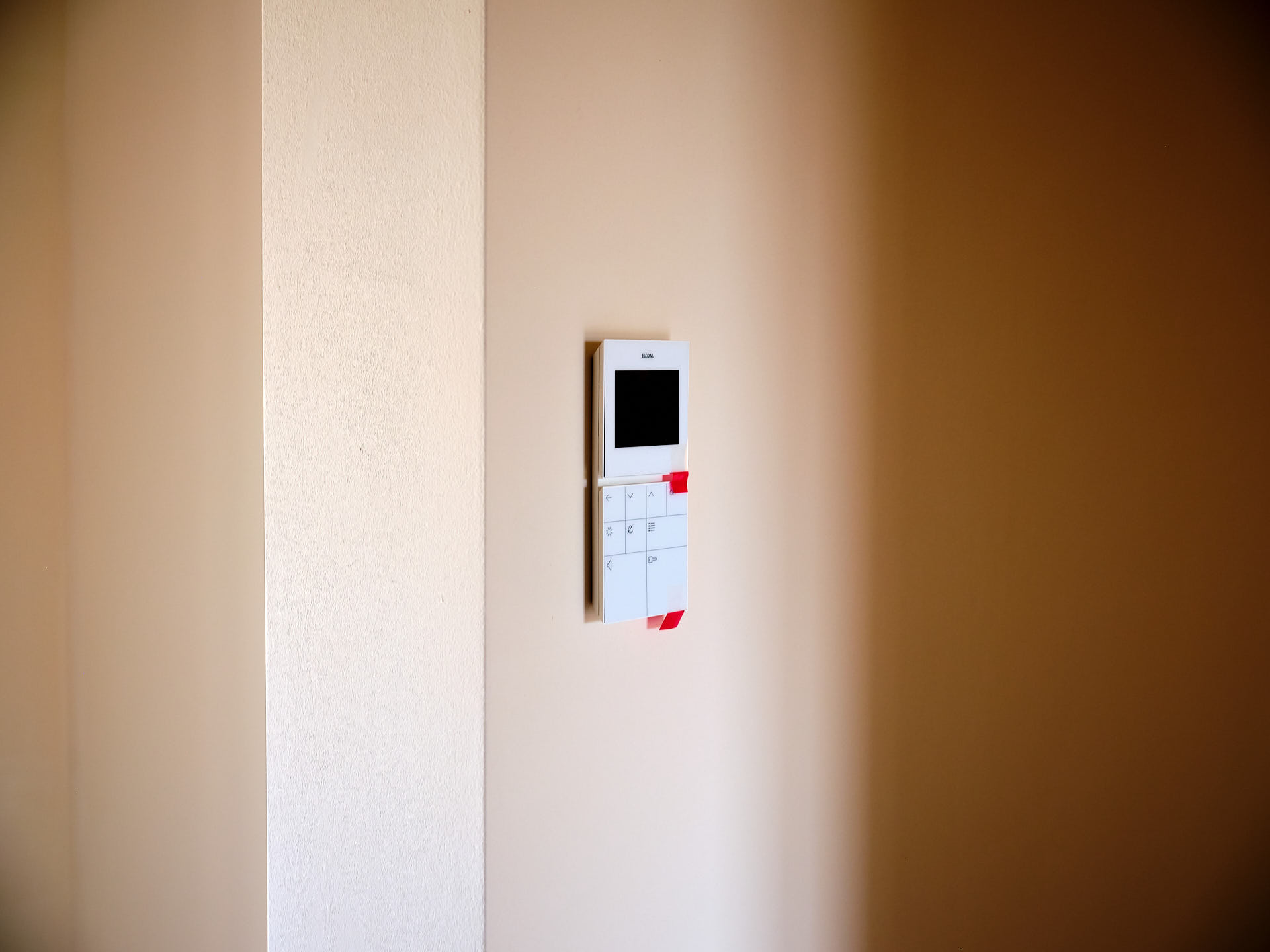 Modernes Smart-Home-Bedienpanel an einer mit natürlichem Lehminnenputz gestalteten Wand zur effizienten Steuerung der Haustechnik.